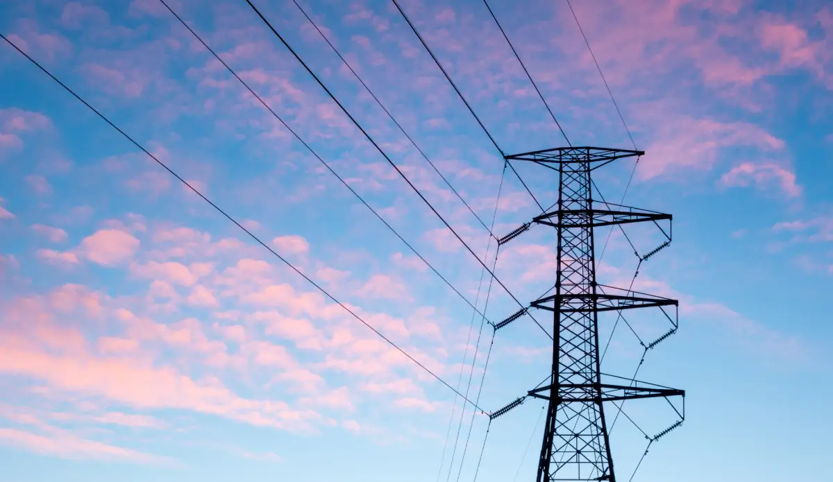 Electricity infrastructure with power lines and substations in a clear blue sky.