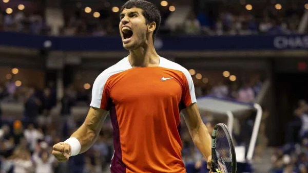 Carlos Alcaraz célèbre sa victoire à Wimbledon contre Djokovic, sourire aux lèvres, trophée en main.