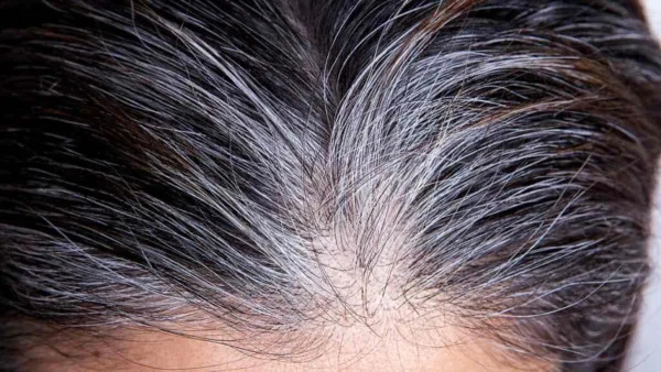 la tête d'une femme dévoilant des cheveux au milieu des cheveux noirs