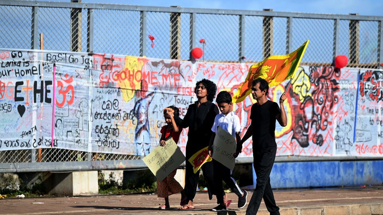 Une famille marche lors des célébrations du Nouvel An à Colombo, entourée de manifestants devant le bureau du président.
