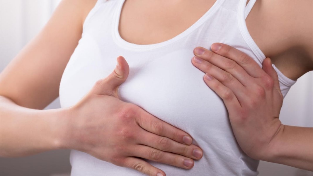 une femme tenant l'un de ses seins avec ses deux mains