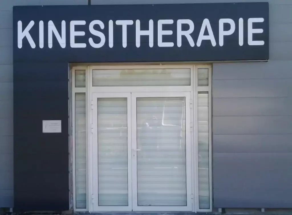 Enseigne de kinésithérapie avec logo et informations de contact.