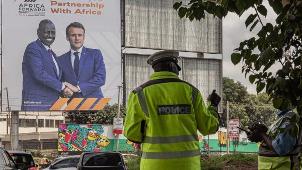 Des policiers kényans régulent la circulation devant un panneau d'affichage présentant une image du président kényan William Ruto et du président français Emmanuel Macron, faisant la promotion du prochain sommet conjoint Kenya-France « Africa Forward » qui se tiendra à Nairobi le 11 mai 2026.