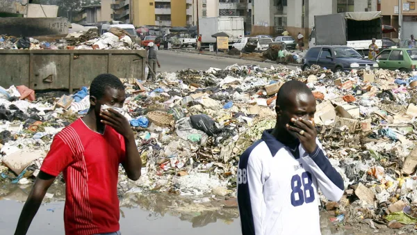 Des hommes se protègent des odeurs nauséabondes le 13 septembre 2006 devant une décharge dans un quartier d'Abidjan. Une importante quantité de déchets toxiques, déversée par une multinationale néerlandaise dans la capitale ivoirienne, se trouve en mer et à proximité de zones maraîchères, a déclaré un représentant de l'ONU, craignant une contamination de la chaîne alimentaire. Selon les autorités ivoiriennes, six personnes, dont quatre enfants, sont décédées et 10 000 ont consulté dans plus de 30 centres de santé depuis le déversement des déchets en août.