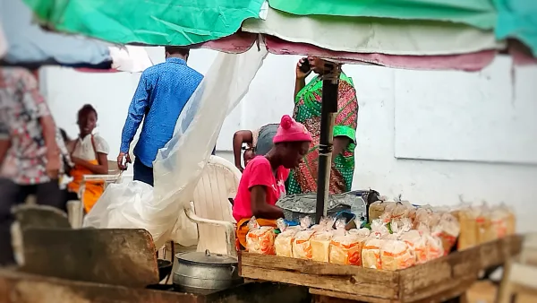 Une femme fait frire et vend de l’akara, des haricots et du pain au bord d’une route au Nigeria